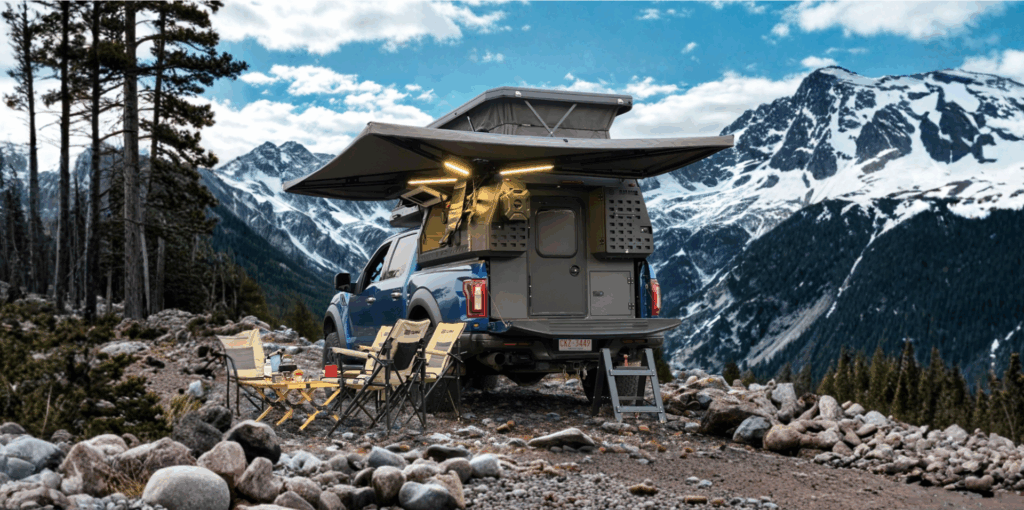 A camper trailer on a 4x4 truck in the mountains.