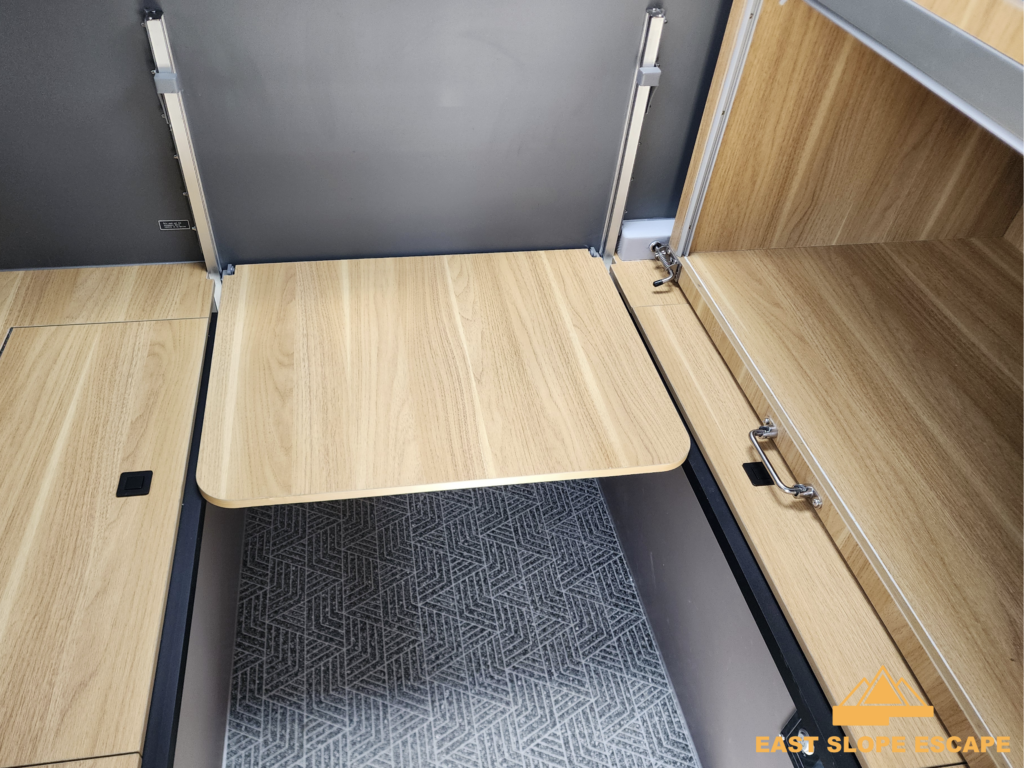 A foldable table is extended inside of a camper.