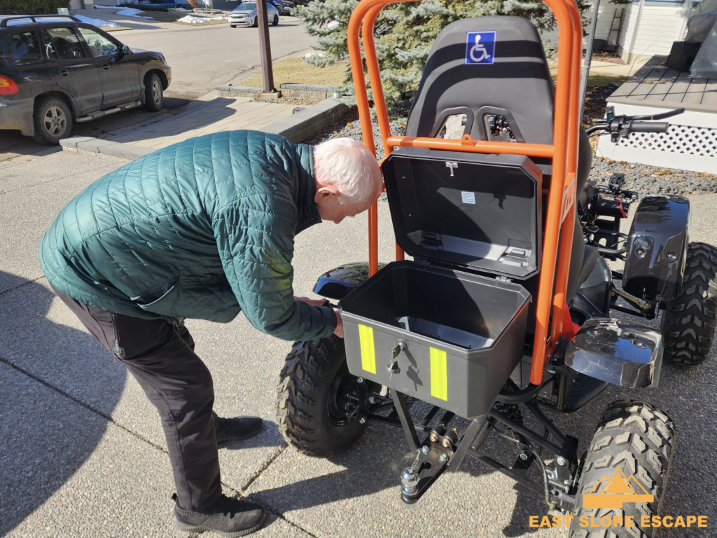 A man looking inside of a compartment on the back of an ATV